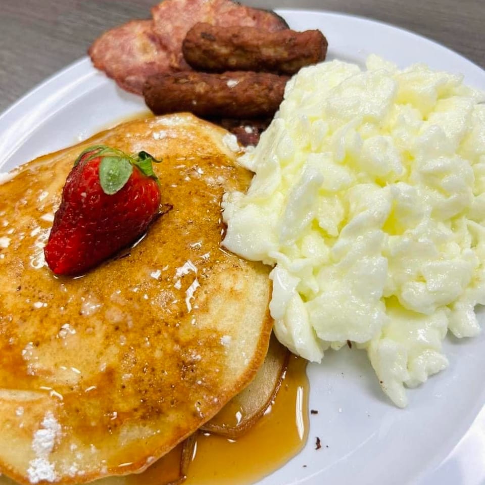 Chef Flavas' breakfast plate with pancakes, scrambled eggs, sausage links, and bacon.